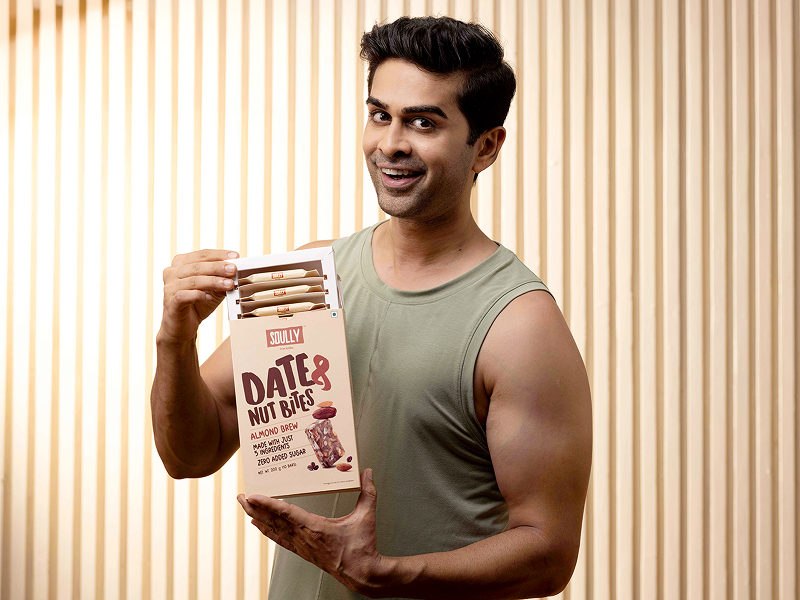 Man holding a package of Soully Foods 'Date Nut Bites' against a beige background